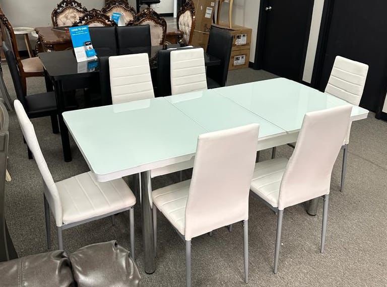 White glass-top dining table with 6 white chairs
